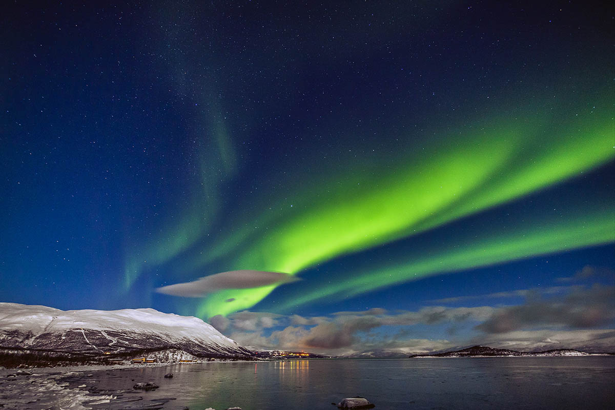 Aurora Borealis appears over Tornetrask Lake and Mount Nuolja in Swedish Lapland