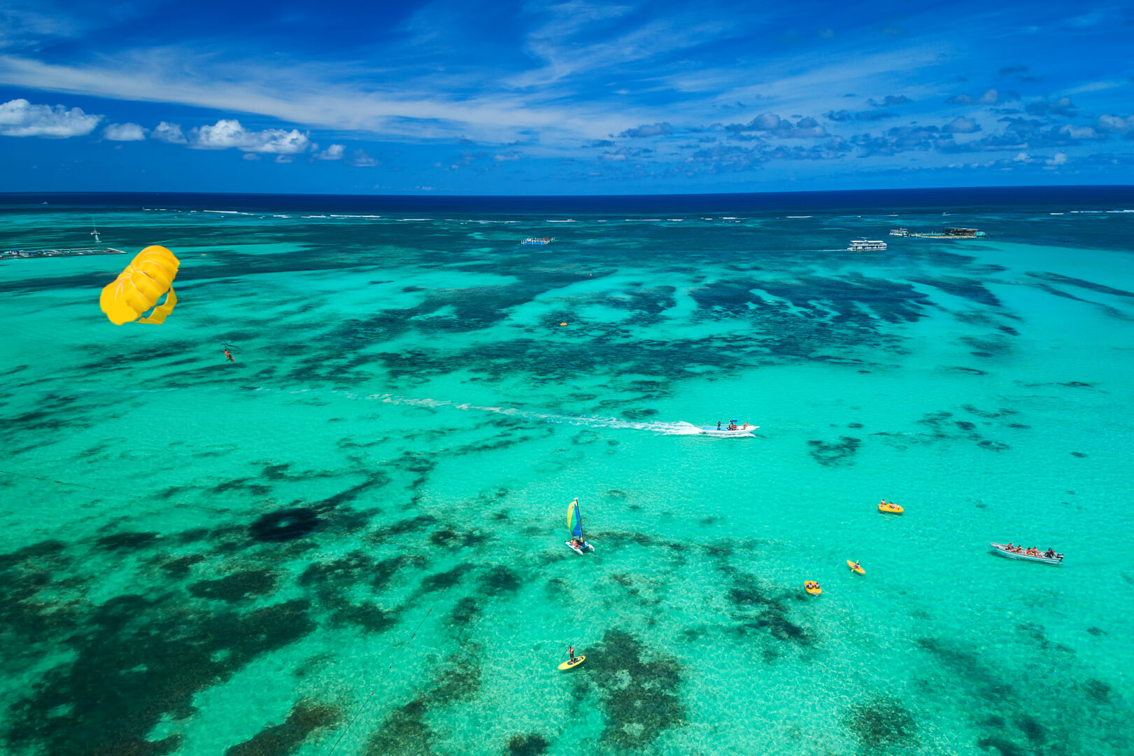 Aerial drone view of people enjoying water sports sea activities for sport, fun, leisure or recreational pursuit near Punta Cana beach. Caribbean sea.